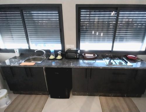 a kitchen counter with a sink and two windows at Beautiful apartment next to airport Mohamed V in Derroua