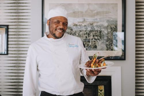 a chef is holding a plate of food at Valley Lodge - Babanango Game Reserve in Dundee