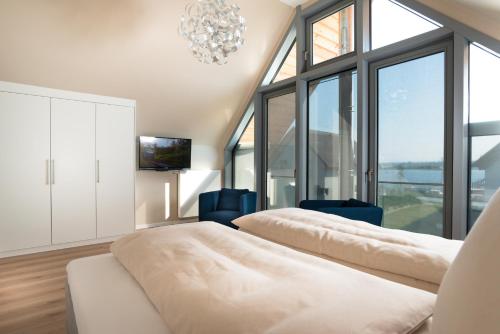 two beds in a room with a chandelier and windows at Ostsee - Reetdachhaus Nr 38 "RIKE" im Strand Resort in Heiligenhafen