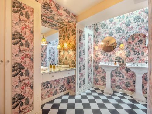 uma casa de banho com papel de parede floral, 2 lavatórios e um espelho em Ridge Hill Manor em Turners Hill