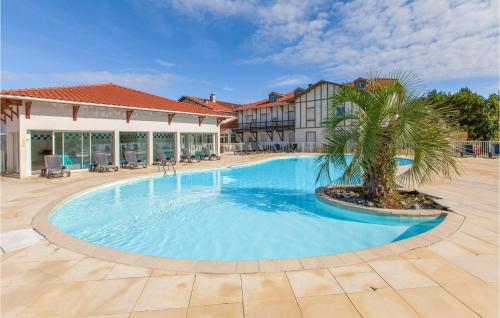 une grande piscine avec un palmier en face d'un bâtiment dans l'établissement Lovely Apartment In Cassen With Outdoor Swimming Pool, à Cassen