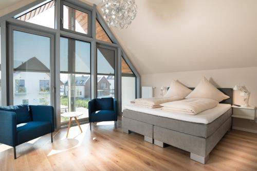 a bedroom with a bed and a blue chair at Ostsee - Reetdachhaus Nr 37 "RENATE" im Strand Resort in Heiligenhafen