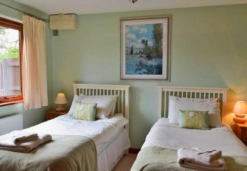 a bedroom with two beds and a picture on the wall at Finest Retreats- Little Dunley - Oaktree Cottage in Bovey Tracey