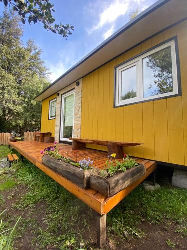 a yellow tiny house with a wooden deck at Amapola Tiny House in San Carlos de Bariloche