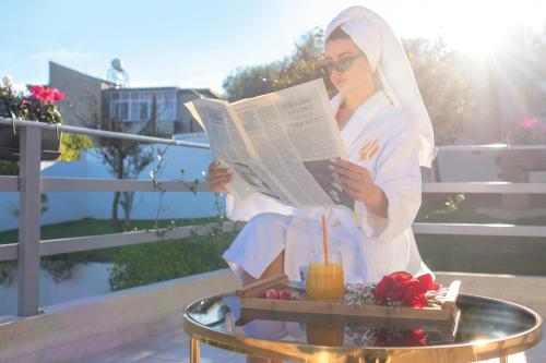 a woman sitting on a table reading a newspaper at ELITE LUXURY BOUTIQUE in Fier