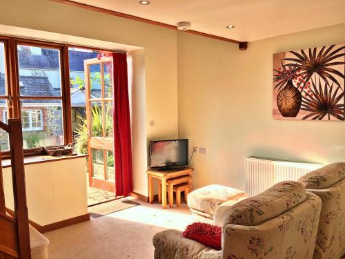 a living room with two chairs and a television at Finest Retreats - Little Dunley - Fig Cottage in Bovey Tracey