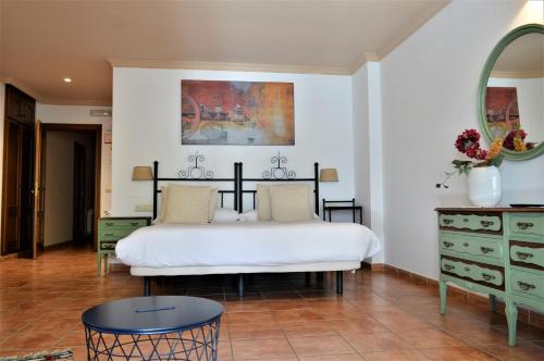 a bedroom with a white bed and a mirror at Hotel Rural Alfajía de Antonio in Capileira