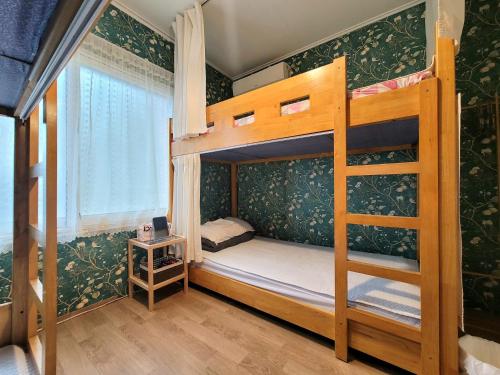 a bedroom with two bunk beds and a window at Greenday Guesthouse in Jeju