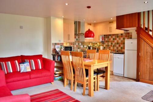 uma sala de estar com um sofá vermelho e uma mesa em Finest Retreats - Little Dunley - Wisteria Cottage em Bovey Tracey