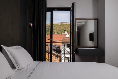 Schlafzimmer mit einem Bett und einem Fenster mit Aussicht in der Unterkunft Triumf Hotel in Prizren