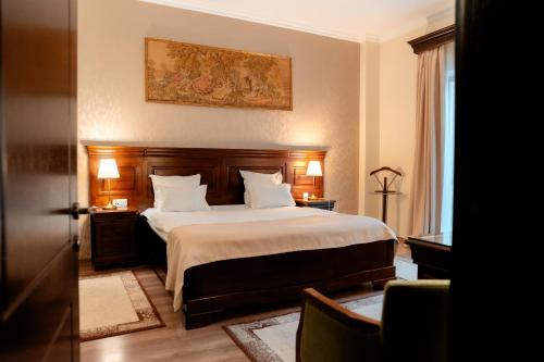 1 dormitorio con 1 cama grande con sábanas y almohadas blancas en Grand Hotel Sofianu, en Râmnicu Vâlcea