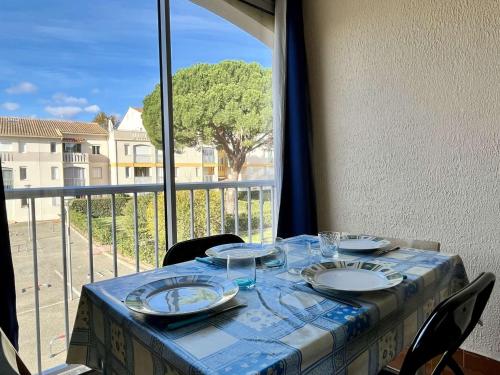 une table avec des assiettes et des verres sur un balcon dans l'établissement Appartement Studio/Cabine 4 pers, Proche Plage, Garage Privé - Argelès-sur-Mer - FR-1-225-17, à Argelès-sur-Mer