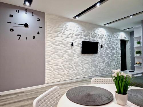 a wall with a clock and a table and chairs at Premium apartment on Belvedere in Ivano-Frankivsk