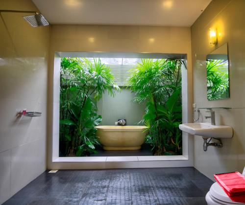 a bathroom with a tub with plants inside of it at Hideaway Villa in Laem Set Beach