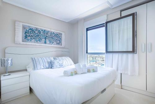 a white bedroom with a large bed and a window at Old Port, apartamento con vistas al puerto in Bermeo