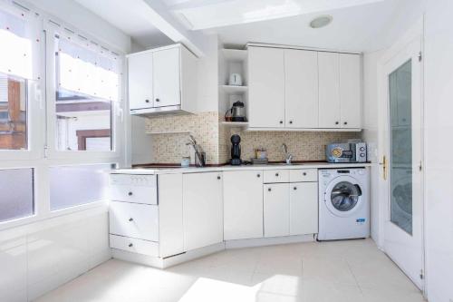 a white kitchen with white cabinets and a washing machine at Old Port, apartamento con vistas al puerto in Bermeo