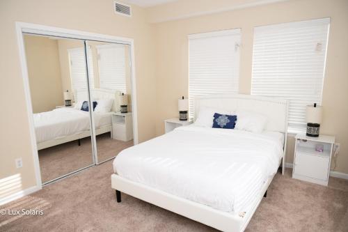 Schlafzimmer mit einem weißen Bett und einem Spiegel in der Unterkunft Luxury 3 Bedrooms with King bed Downtown Indy in Indianapolis