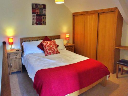sypialnia z dużym łóżkiem z czerwoną i białą pościelą w obiekcie Finest Retreats - Little Dunley - Virginia Cottage w mieście Bovey Tracey