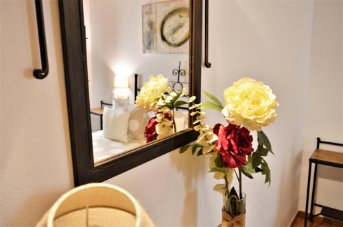 a mirror with a vase of flowers on a table at Hotel Rural Alfajía de Antonio in Capileira