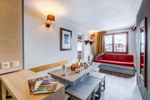 a living room with a table and a red couch at Vacancéole - Le Borsat IV in Tignes