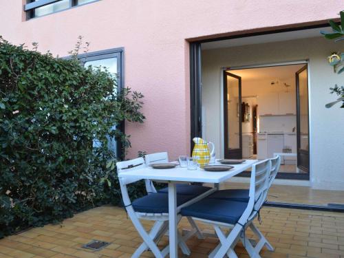 une table blanche et des chaises assises sur une terrasse dans l'établissement Appartement T2 avec terrasse, piscine, proche plage à Saint-Cyprien - FR-1-225D-26, à Saint Cyprien Plage