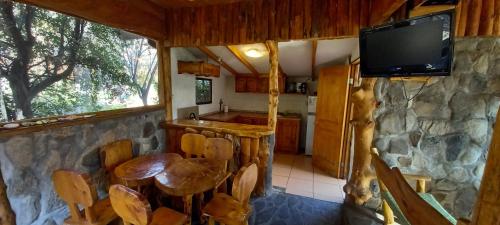 a kitchen with a table and a tv on a stone wall at Tres Continentes in San José de Maipo