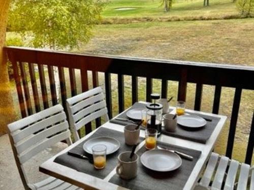 - une table avec des assiettes et des boissons sur le balcon dans l'établissement Appartement Montgenèvre 4 pers, parking, départ skis aux pieds - FR-1-330D-54, à Montgenèvre