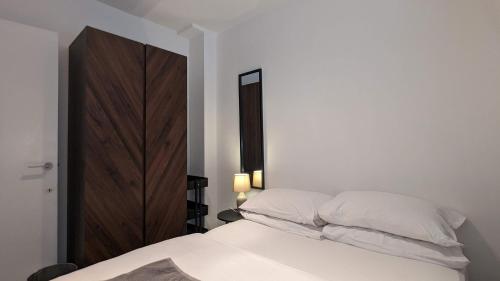 a bedroom with a white bed and a wooden cabinet at Cozy Urban Oasis: Stylish One Bedroom Flat on Old Compton Street in London