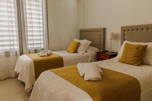 1 dormitorio con 2 camas con almohadas amarillas en ALTA VISTA APART HOTEL en Reconquista