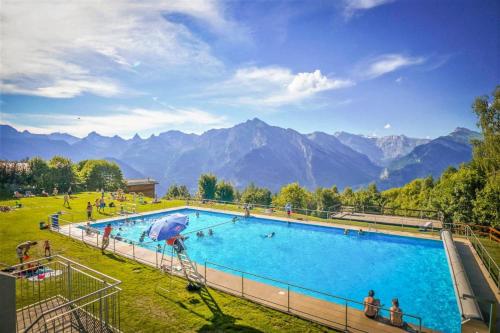 a large swimming pool with mountains in the background at Pracondu RENOVE OUTDOOR & FUN Appartement 8 personnes in Nendaz