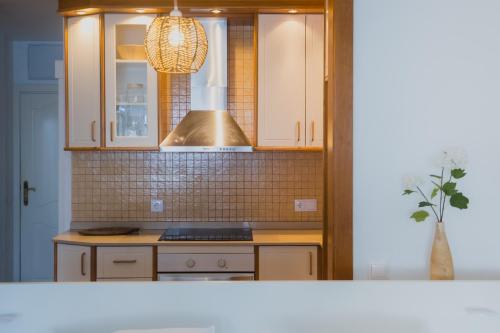 a kitchen with white cabinets and a stove top oven at Sobre el mar con vistas a las Dunas de Maspalomas in San Agustin