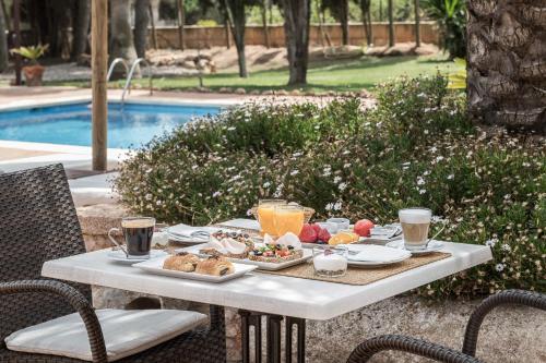 a table with breakfast food on it next to a pool at Finca Es Torrent in Campos