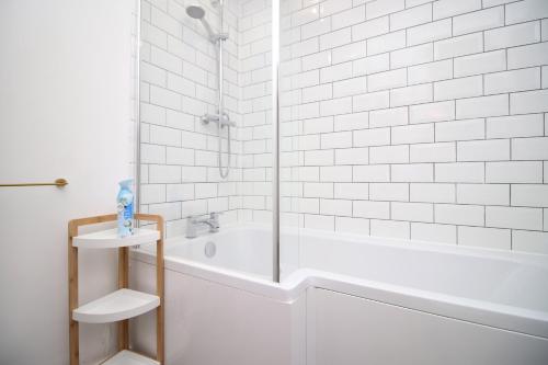 een witte badkamer met een douche en een bad bij K Suites - Seymour Street in Mountain Ash