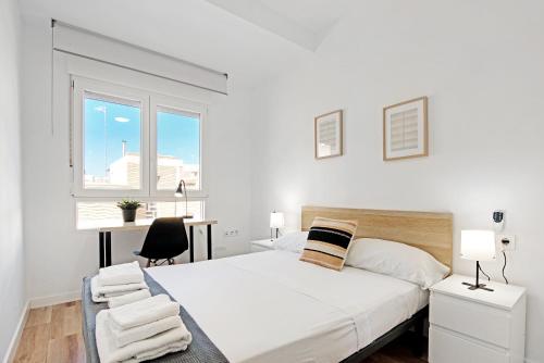 a white bedroom with a large bed and a window at Palmereta in Sagunto
