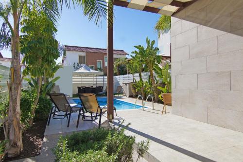 een patio met een tafel en stoelen naast een zwembad bij Villa Maris in Protaras