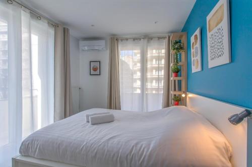 a bedroom with a white bed with a blue wall at Alberts Cocooning in Grenoble