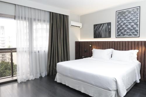 a bedroom with a white bed and a large window at Double Tree by Hilton São Paulo Itaim in São Paulo