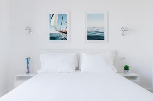 a white bedroom with three pictures on the wall at Puolo Seaside Apartment 2 in Massa Lubrense