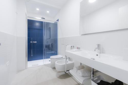 a white bathroom with a toilet and a sink at Puolo Seaside Apartment 2 in Massa Lubrense