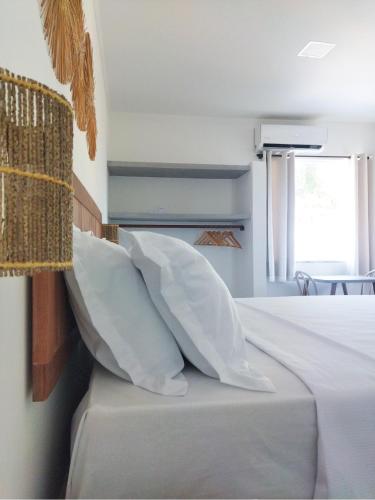 a bedroom with white pillows on a bed with a window at Pousada Fenícia in Japaratinga