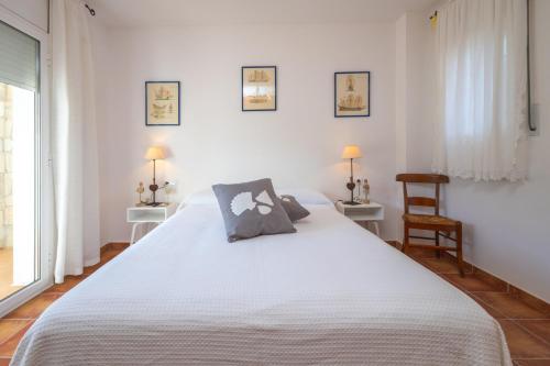 a bedroom with a large white bed with two chairs at Villa Dolly in Calonge