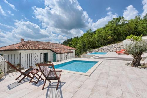 a patio with a pool and two chairs and a house at Villa Lapis in Buzet