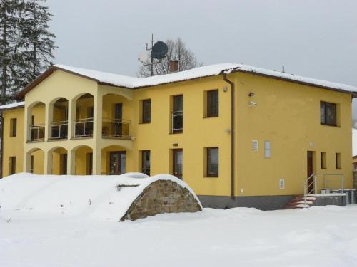 un edificio amarillo con nieve delante en Wellness Villa Liptov, en Liptovská Sielnica