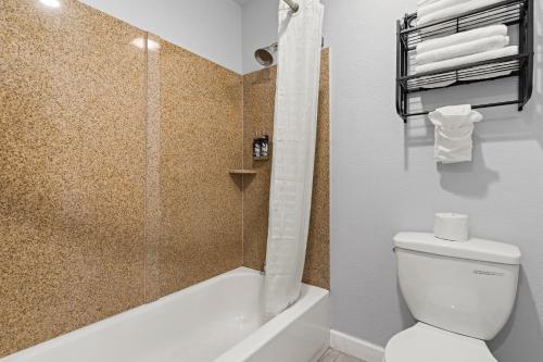 a bathroom with a shower and a toilet and a tub at Bay Breeze Inn in Oakland