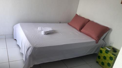 białe łóżko z 2 poduszkami i ręcznikami w obiekcie Ytamãní ll apartamentos w mieście Santa Cruz Cabrália