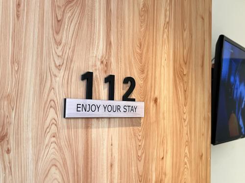 a sign on a wooden door that reads enjoy your stay at Apple 1 Hotel Gurney in George Town