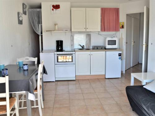 une cuisine avec des appareils blancs et une table dans une pièce dans l'établissement Appartement Climatisé 2 Pièces avec Balcon et Garage Privatif à Cavalaire-sur-Mer - FR-1-226B-101, à Cavalaire-sur-Mer