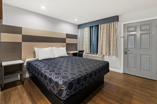 a bedroom with a bed and a desk and a window at Bay Breeze Inn in Oakland