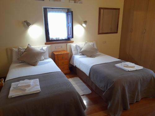 two beds in a small room with a window at Casa del Horno in Potes