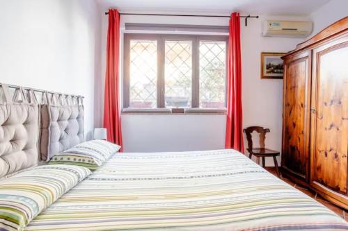 a bedroom with a bed with red curtains and a window at Casa Paradiso sul Mare delle Aci in Aci Catena